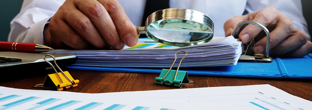 An Auditor Reviewing Documents with a Magnifying Glass